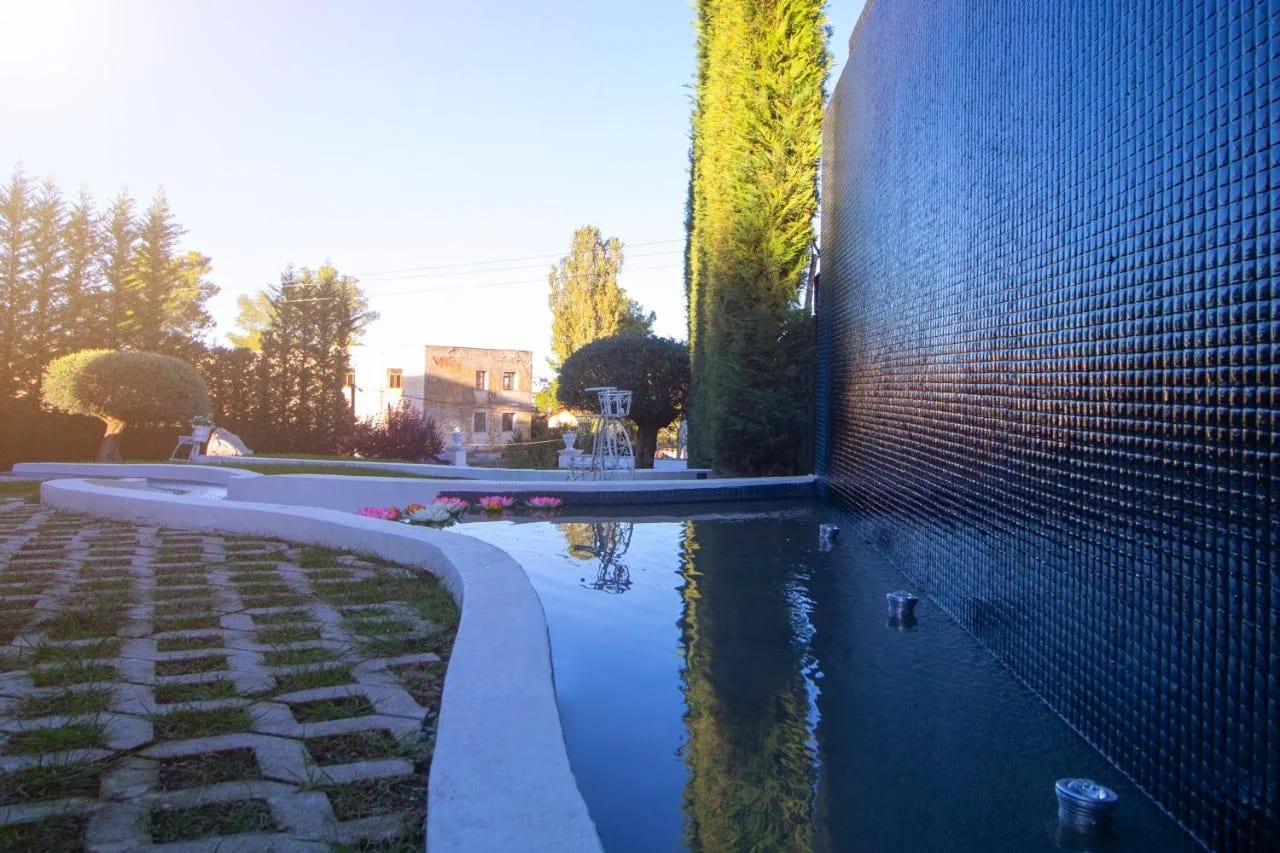 A narrow mosaic-tiled water channel running beside the lawn and stone paving